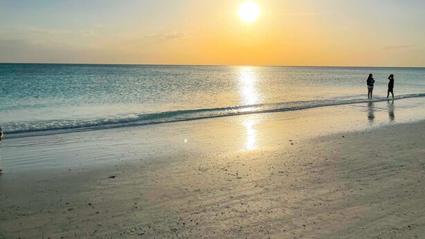 A beach scene with two people standing near the water's edge during sunset. - The Coral Cottage close to all that Sarasota has to offer (Sarasota)