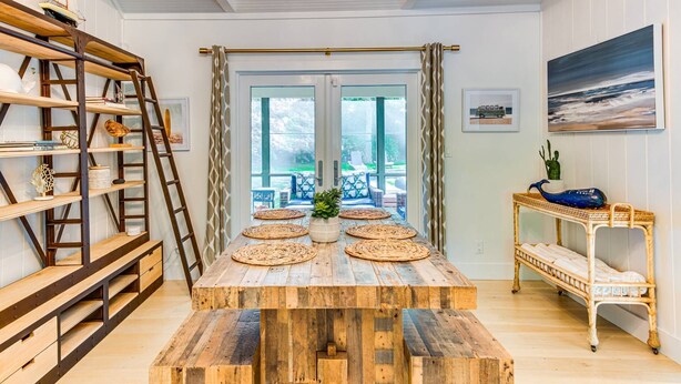 A dining area with a wooden table, wicker chairs, and a ladder. - Oasis heaven close to everything you need! (East Hampton)