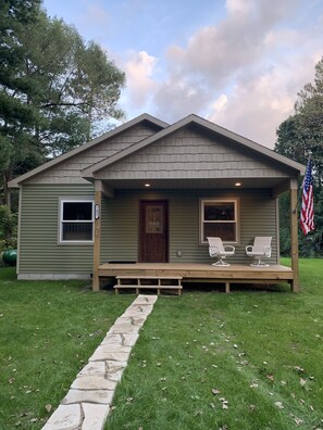 A single-story house with a front porch, a wooden deck, and an American flag.