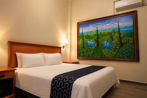 A hotel room with a bed, nightstands, a painting on the wall, and an air conditioning unit. - Hotel Boutique de Firma (Monterrey)