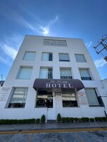 Un edificio blanco con un letrero que dice 'De Firma Hotel Boutique' y el número 312.