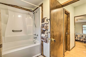 Un baño con una bañera blanca, un perchero con varias toallas y una puerta de madera.