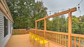 Una terraza de madera con sillas amarillas y barandilla de madera.