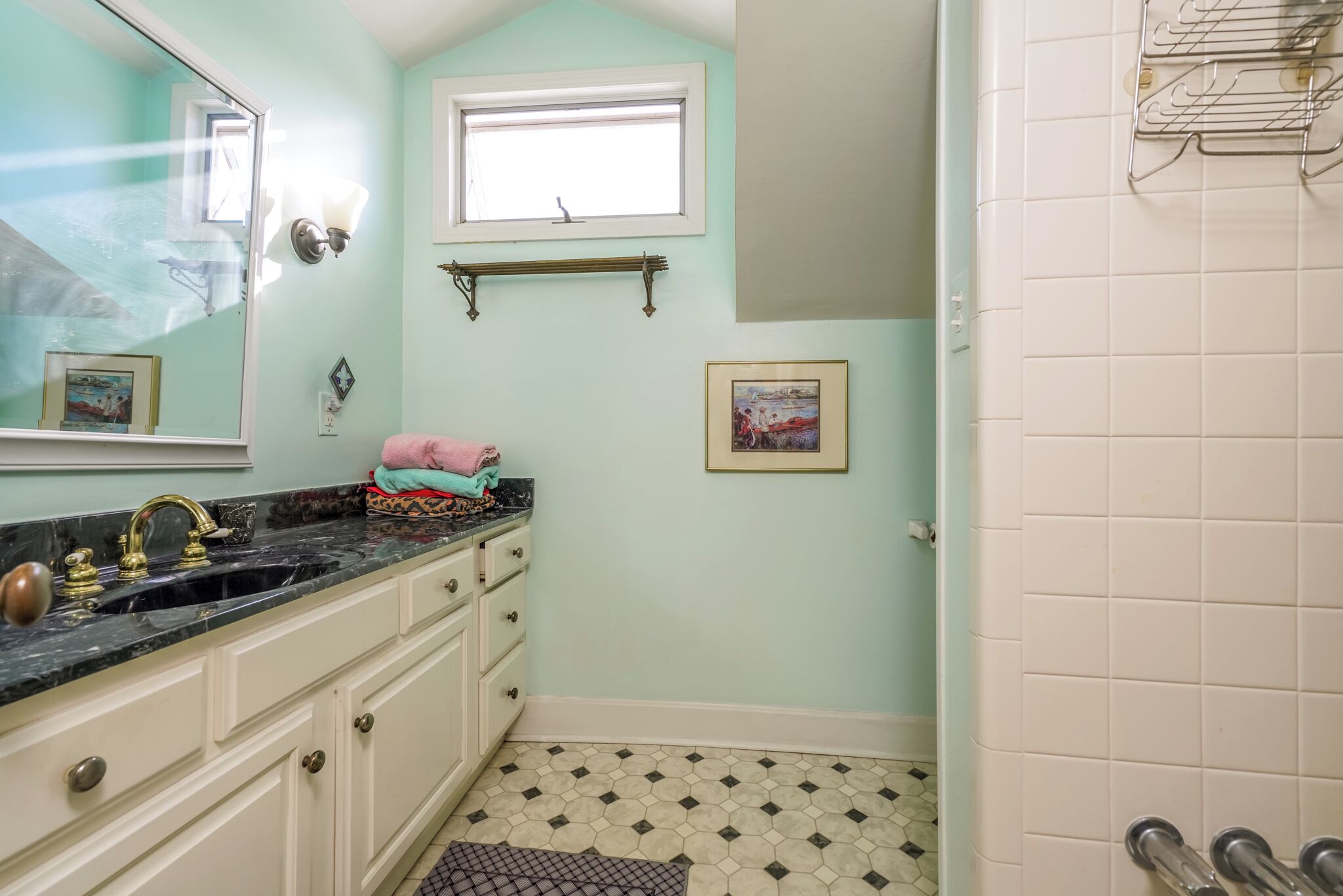 A bathroom with a sink, mirror, and tiled floor.