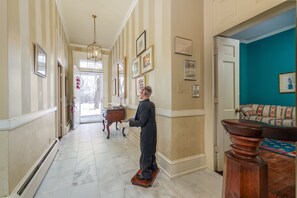 A hallway with a statue, framed pictures, and a teal-colored room at the end. - Cheerful 8-Bedroom, 6-Bath Historic Mansion in Derby City – Ideal Vacation Home! (Louisville)