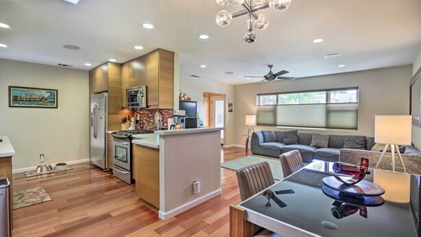 A modern kitchen with wooden cabinets, stainless steel appliances, and a dining area with a glass table. - Updated San Diego Home w/ Private Yard & Patio! (San Diego)
