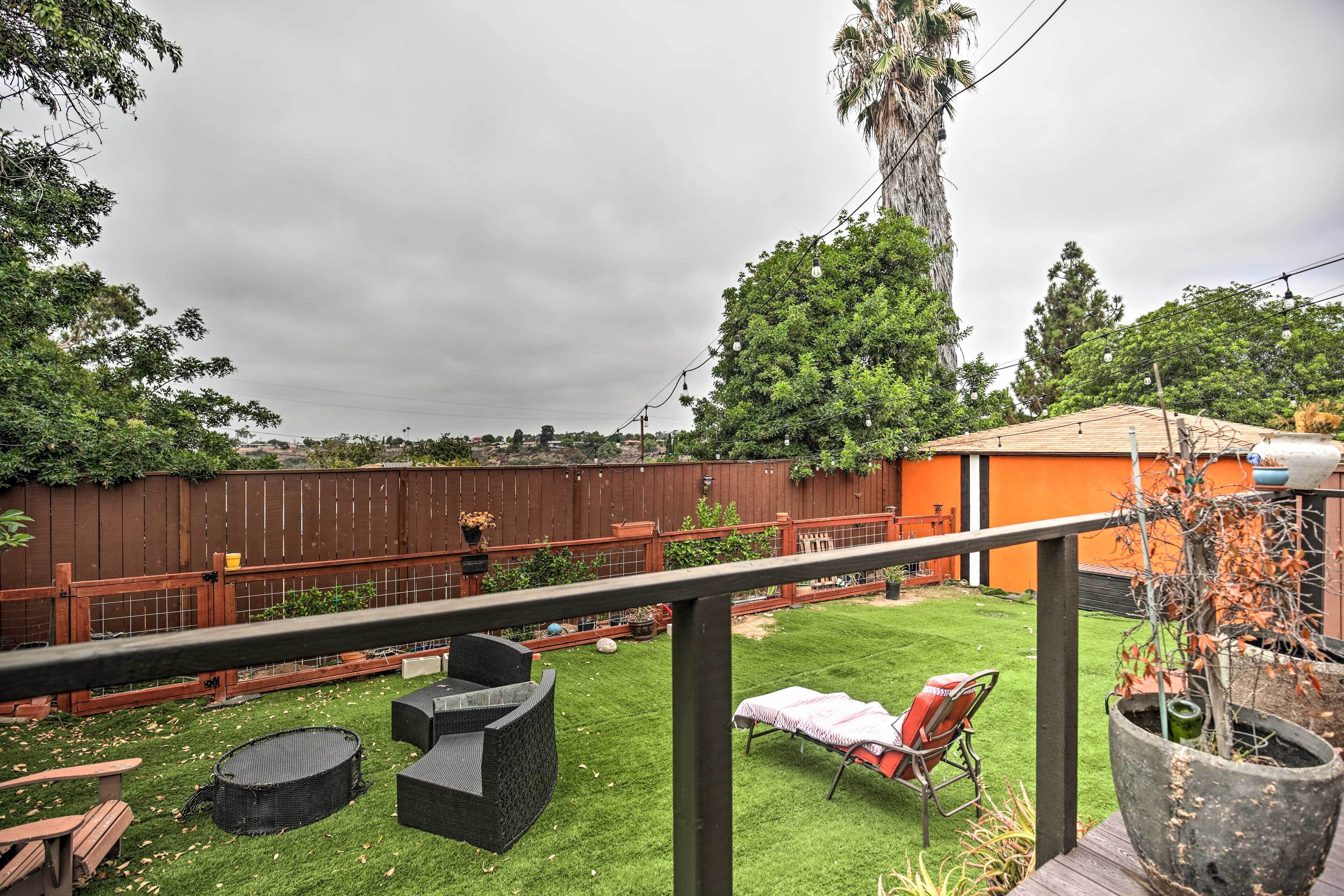 A backyard with a wooden deck, outdoor furniture, a barbecue grill, and a potted plant.