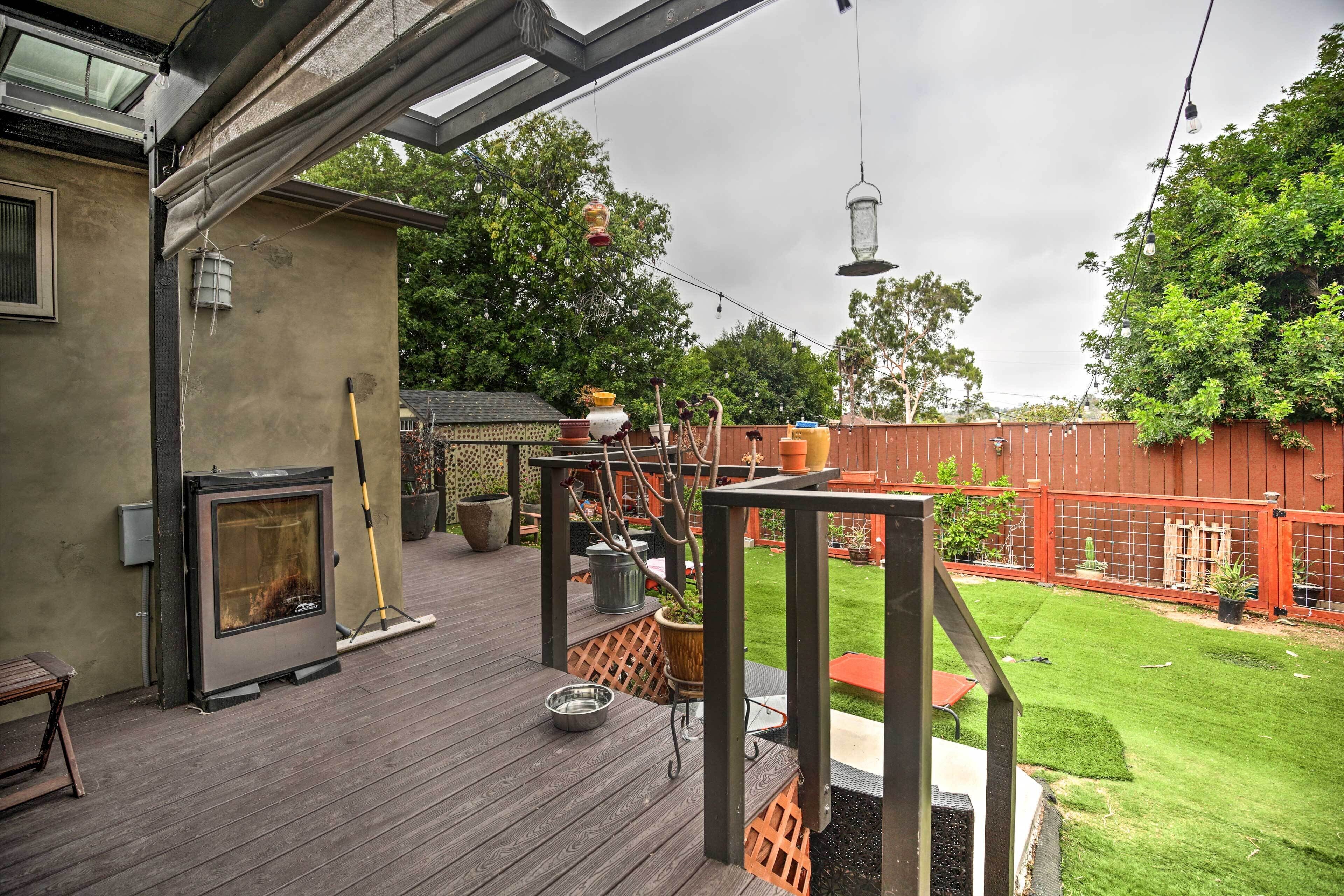 Una terraza de madera con chimenea, césped y patio trasero cercado.