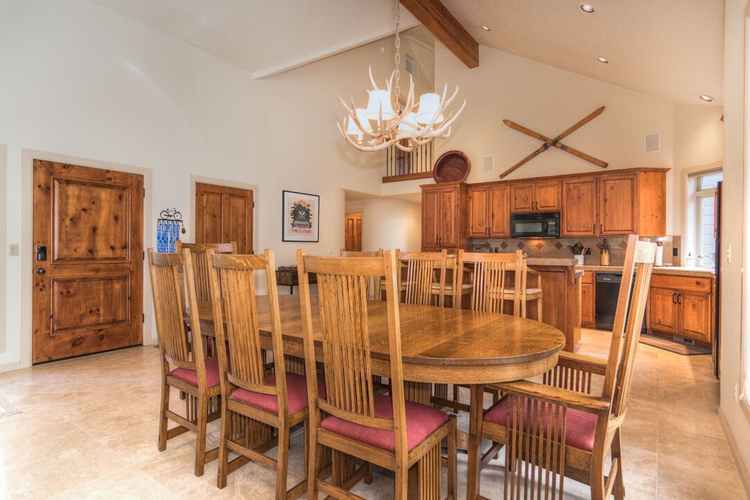 A spacious kitchen with wooden cabinets, a large round table, and chairs.