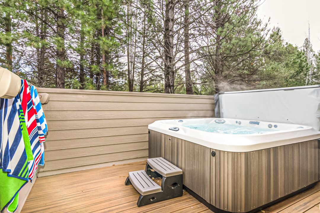 A hot tub on a wooden deck with a view of trees.