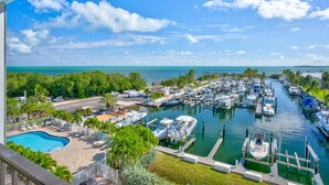 A marina with boats docked, a swimming pool, and a view of the ocean. - Free Kayaks Overlooking Pickleball Courts (Key Largo)