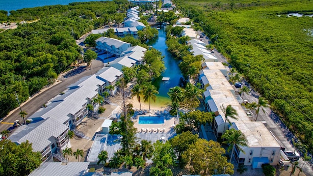 An aerial view of a resort with a central swimming pool, multiple buildings, and a clear view of the ocean. - Free Kayaks Overlooking Pickleball Courts (Key Largo)