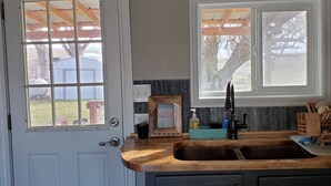 A kitchen with a wooden countertop, a sink, and a window with a view of the outdoors. - Chesterfield-Lava Hot Springs - Farm Cottage (Bancroft)