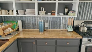 A kitchen with a wooden countertop, a kettle, a stove, and various kitchen utensils. - Chesterfield-Lava Hot Springs - Farm Cottage (Bancroft)