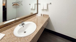 Een badkamer met een wit wastafel, een spiegel en een handdoekhouder.