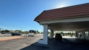 Een tankstation met een overdekte parkeerplaats en een heldere lucht.