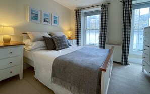 A neatly arranged bedroom with a bed, bedside tables, a dresser, and a window with curtains. - Brakestone Cottage in the heart of Port Isaac (Port Isaac)