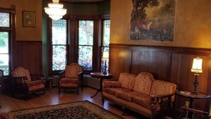 Une pièce au décor traditionnel, avec un canapé, des fauteuils, un lustre et un tableau au mur.