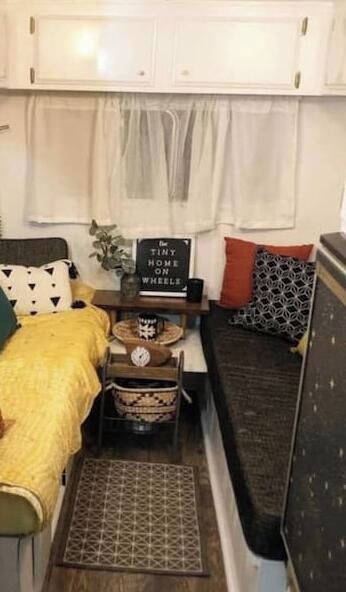 Een compact camperinterieur met een kitchenette, een bed en een klein eethoekje.