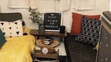 Een compact camperinterieur met een kitchenette, een bed en een klein eethoekje.
