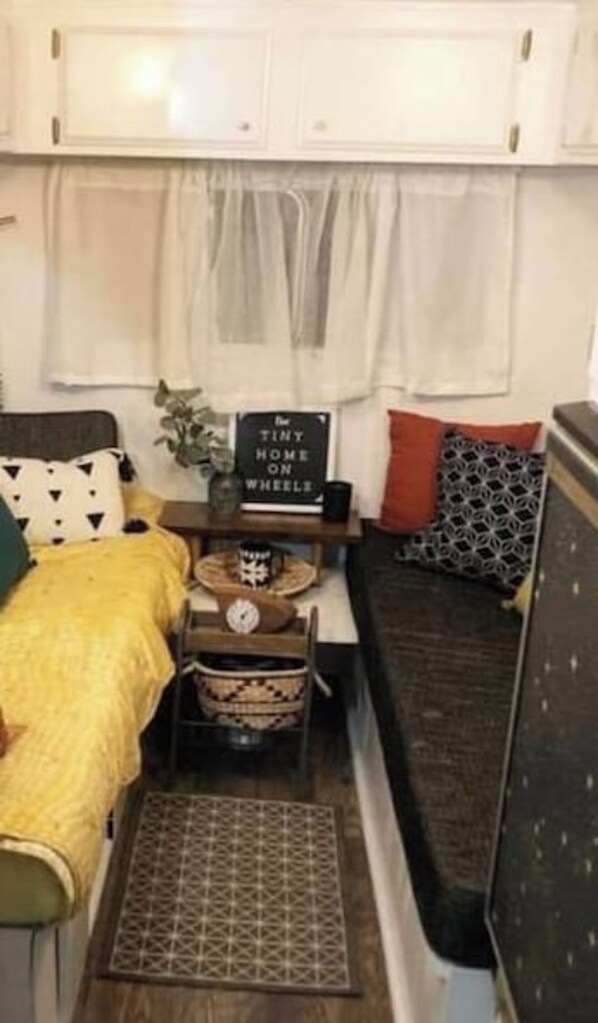A compact living space with a bed, a sofa, a small table, and a sign. - Pleasant Hills Farm Stargazer Farmstay (Darnestown)