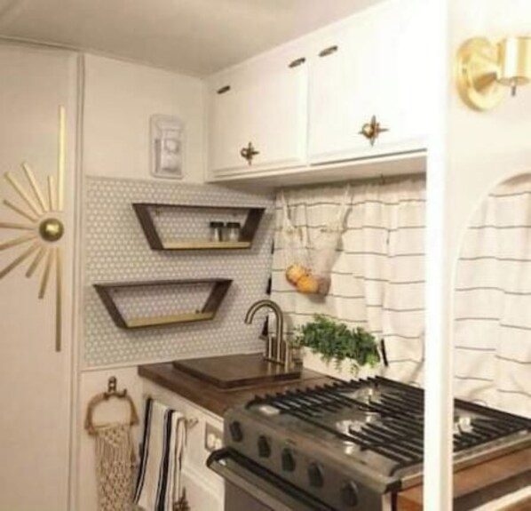 Une cuisine équipée d’une cuisinière, d’un évier et d’une étagère murale décorative.