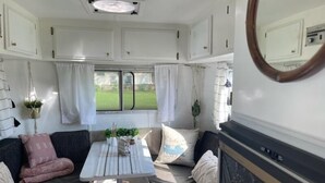 Interior d'una caravana acollidora amb zona de dinar, seients i finestra que ofereix vistes a l'exterior.
