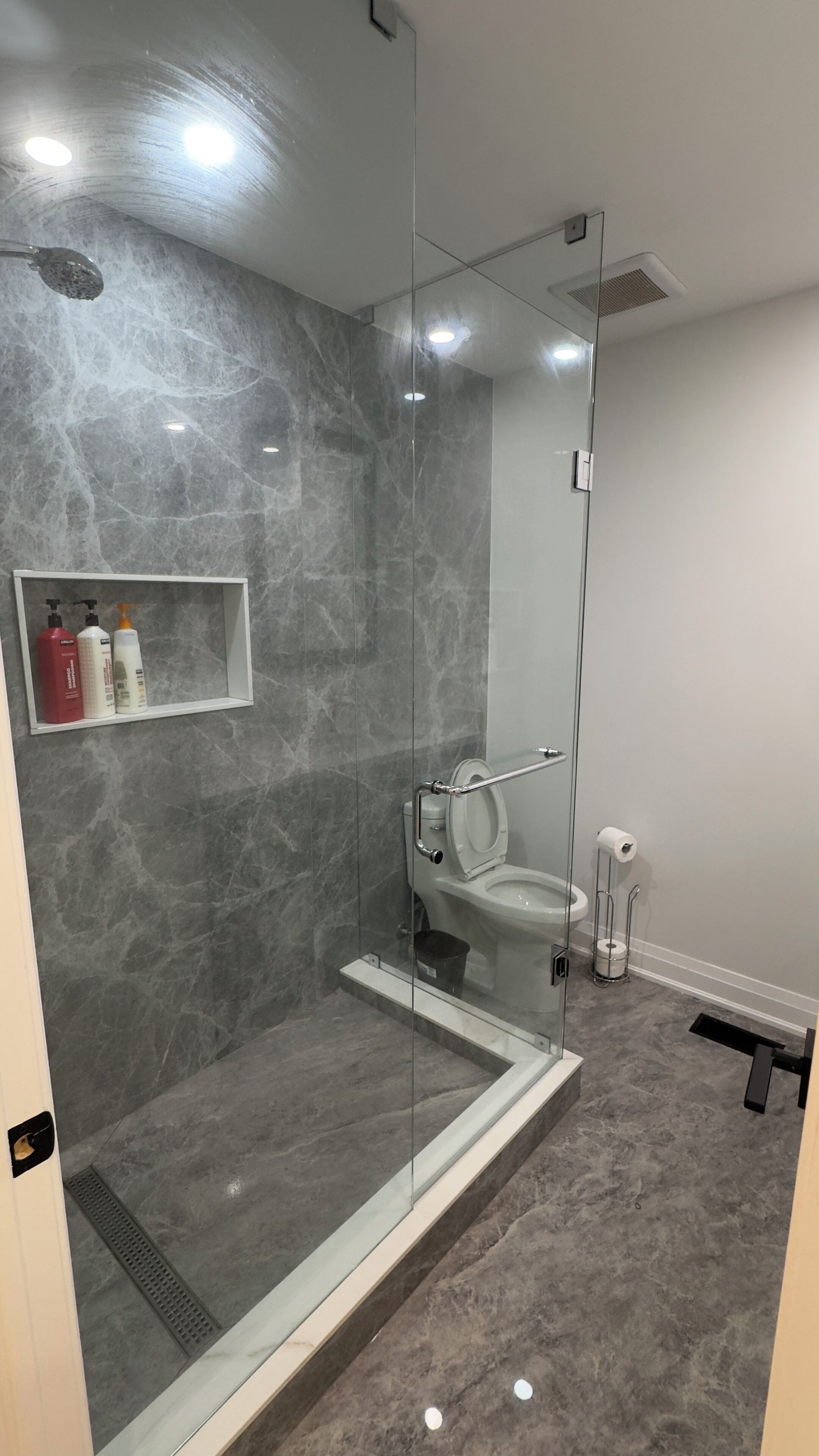 Un bagno moderno con doccia in vetro, un water e un lavandino.
