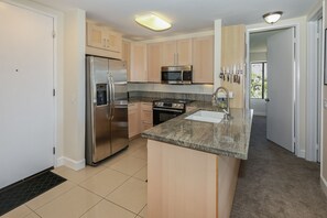 Una cocina moderna con electrodomésticos de acero inoxidable, encimera de granito y armarios de madera.