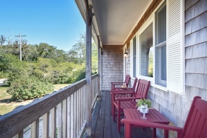 A wooden deck with a railing, a table, and two chairs.