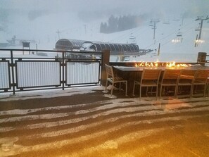 Relax by the fire in this cozy outdoor seating area with a ski lift view.