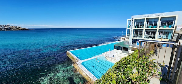 Un hotel sul lungomare con piscina che si affaccia sul mare, una torretta di salvataggio e vista sulla costa.