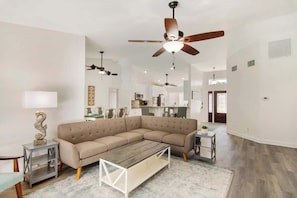 A spacious living room with a sectional sofa, a coffee table, and a ceiling fan. - Beach Getaway - Private Heated Pool & 2 King Beds (Sebastian)
