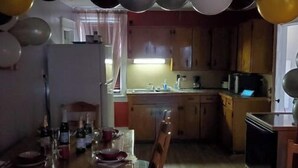 A kitchen with a dining table set for a meal, a refrigerator, and a microwave. - Cozy living.and.dining room (Hudson)