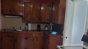 A kitchen with wooden cabinets, a countertop, and a refrigerator. - Cozy living.and.dining room (Hudson)
