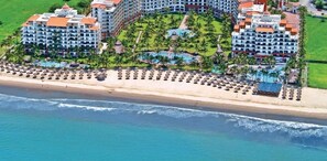 Un complexe hôtelier comprenant plusieurs bâtiments, un accès à la plage et un espace piscine.