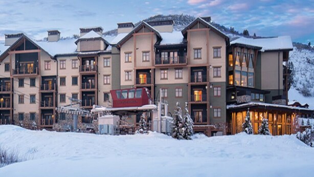 Un hotel de varios pisos con un paisaje nevado, que combina estilos arquitectónicos tradicionales y modernos.