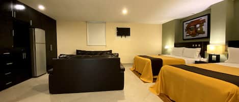 A hotel room with two beds, a sofa, a TV, and a refrigerator.
