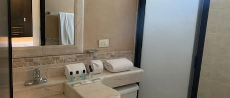 A bathroom with a marble sink, a mirror, a toilet, and a towel rack.