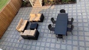 Eine Terrasse mit Tisch, Stühlen und einer Sitzecke, sowie ein kleiner Gartenbereich.