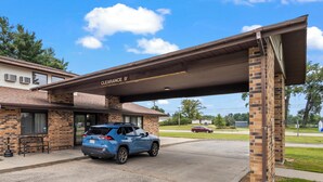 A blue SUV parked under a covered entrance to a building labeled "Clearance 9". - Wautoma Inn by OYO Near Airport WI 73 (Wautoma)
