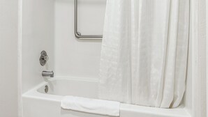 A white bathtub with a shower curtain, a grab bar, and a towel. - Wautoma Inn by OYO Near Airport WI 73 (Wautoma)