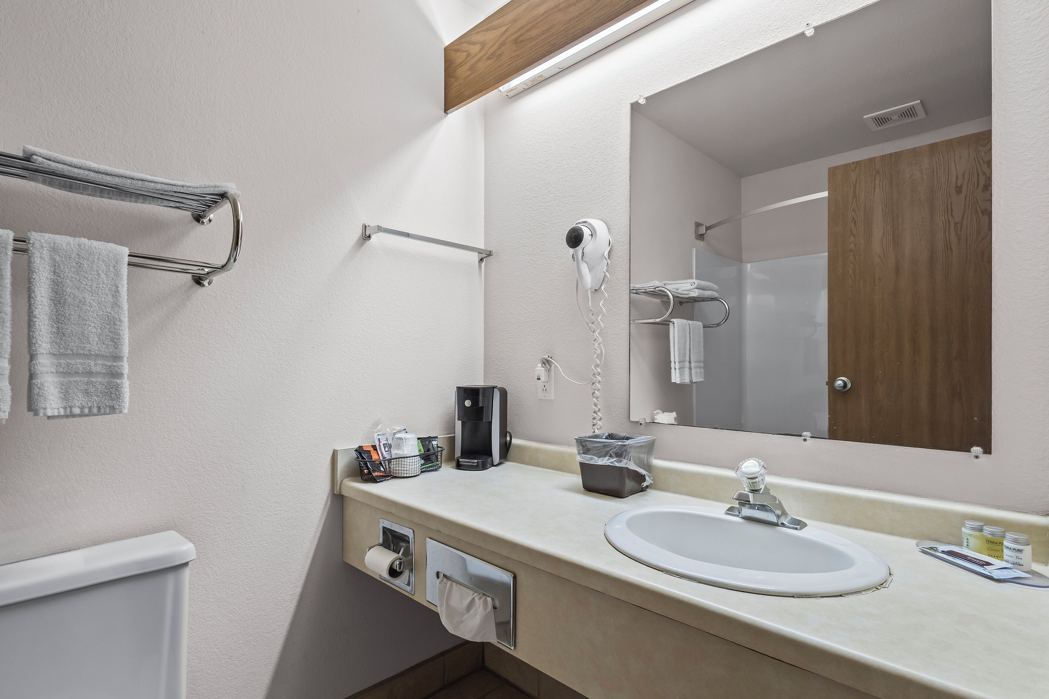 Une salle de bain moderne équipée d’un lavabo, d’un miroir, d’un porte-serviettes, d’un sèche-cheveux et d’articles de toilette.