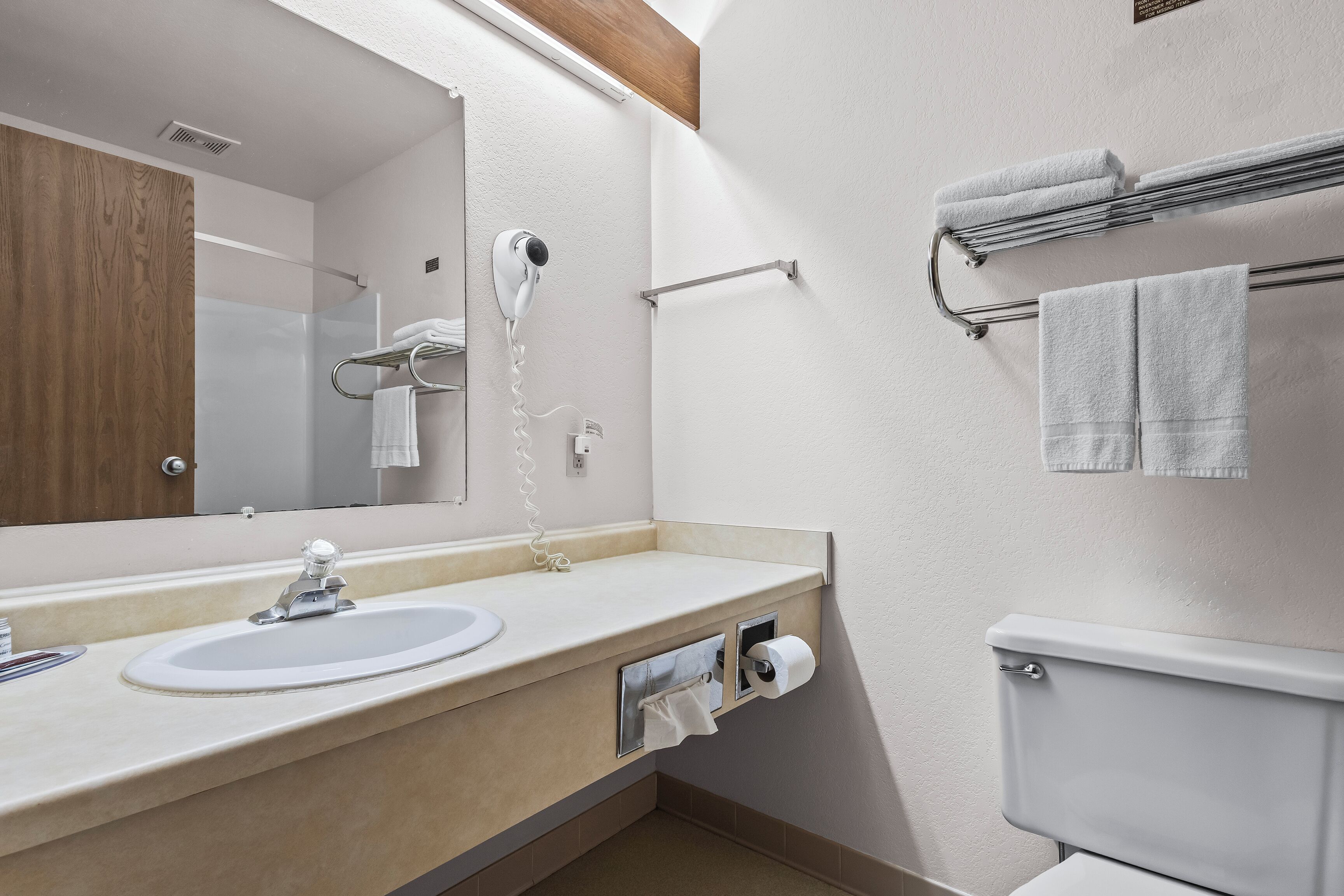 Une salle de bain moderne équipée d’un lavabo, d’un miroir, d’un porte-serviettes et de toilettes.