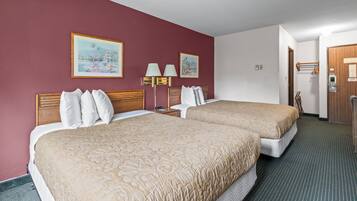 A hotel room with two beds, a painting on the wall, a nightstand, and a door to the bathroom.