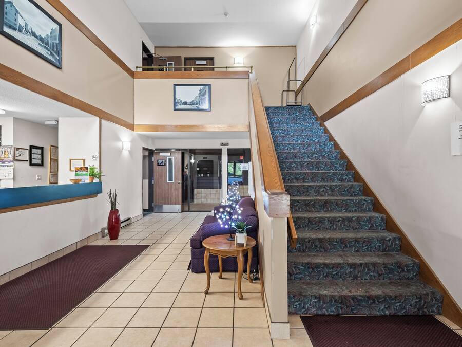 Un vestíbulo de hotel con mostrador de recepción, una escalera y una zona de estar con sofá y una mesita.