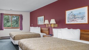 A hotel room with two beds, a window with curtains, a painting on the wall, and a nightstand with a lamp. - Wautoma Inn by OYO Near Airport WI 73 (Wautoma)