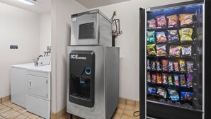 A laundry room with a washing machine, an ice dispenser, and a vending machine with snacks. - Wautoma Inn by OYO Near Airport WI 73 (Wautoma)