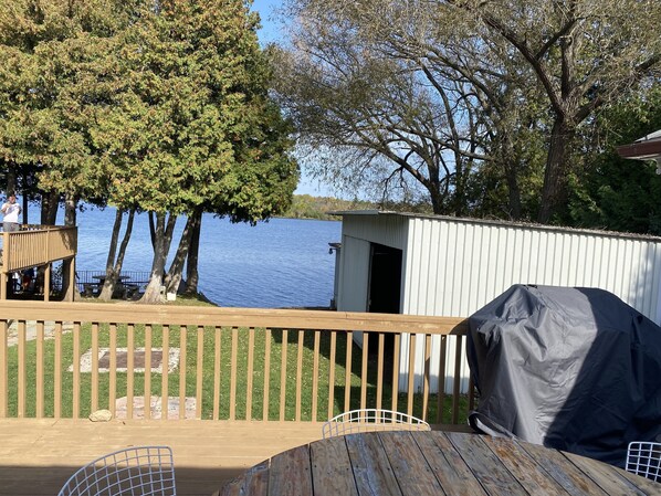 Un muelle de madera con una parrilla, un cobertizo pequeño y vistas a un lago.