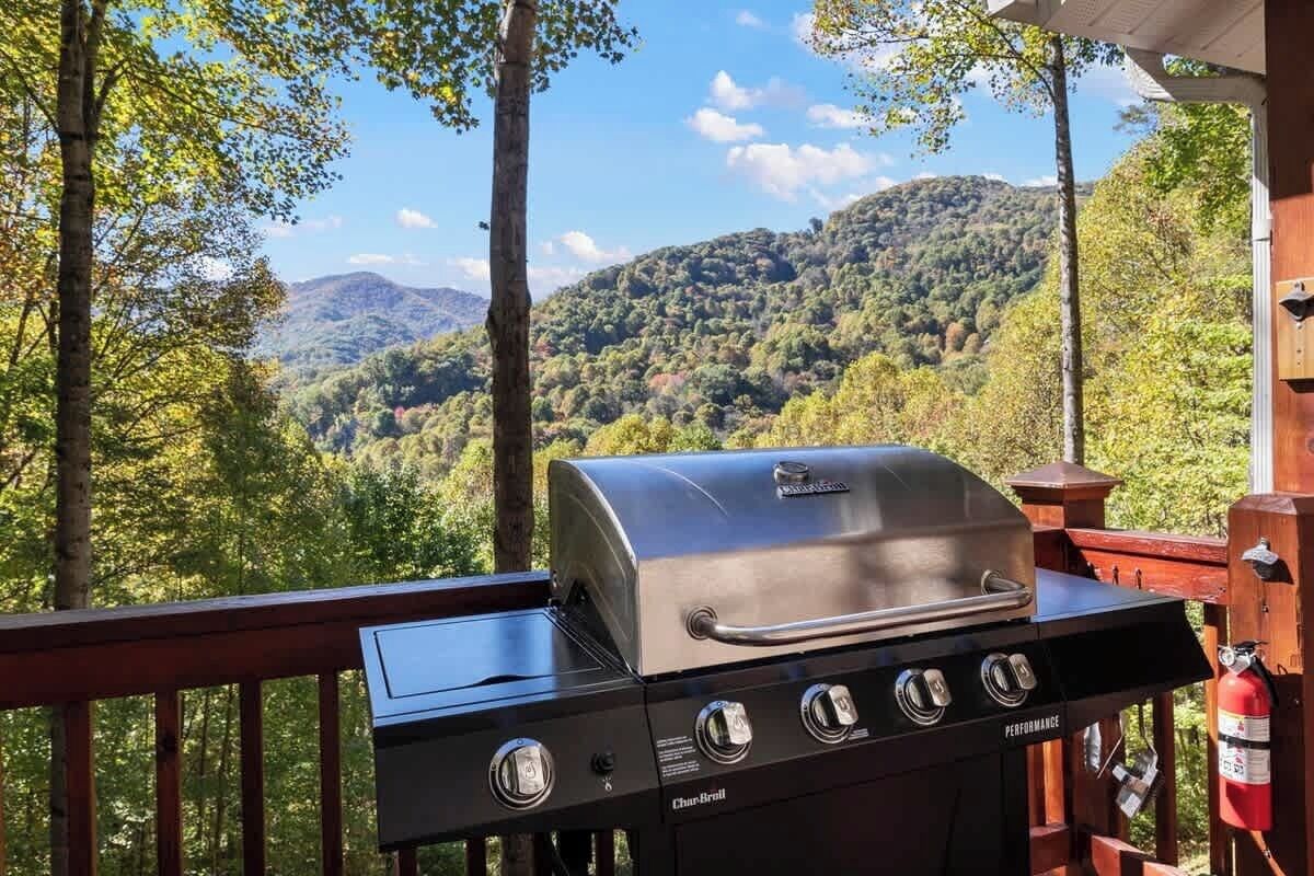 A Char-Broil grill on a wooden deck with a view of a forested mountain range.